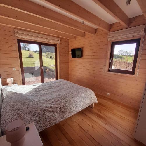 ein Schlafzimmer mit einem Bett in einem Holzzimmer in der Unterkunft Le gîte Pierre et Bois in Houffalize
