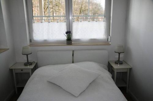 a bedroom with a white bed with two nightstands and a window at Ferienwohnung Melrose - Design & Glasfaser am Silbersee in Lehmbraken