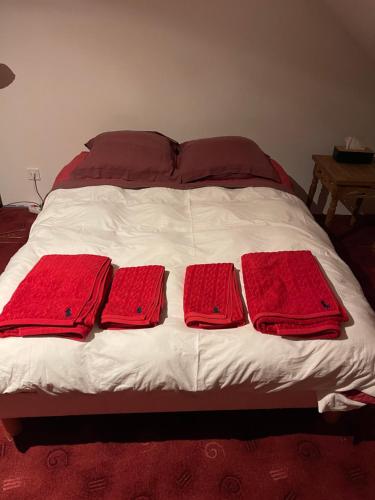 uma cama com quatro toalhas vermelhas em Maison bonheur proche GIVERNY et top pour télétravail 