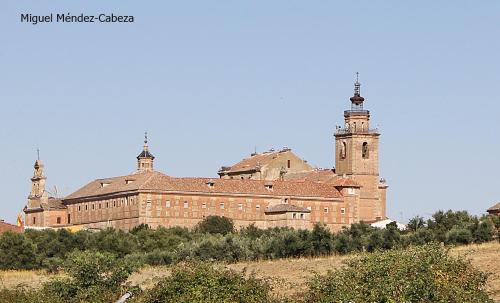a large brick building with a clock tower on a hill at Casa Rural Teralba 2 in La Calzada de Oropesa