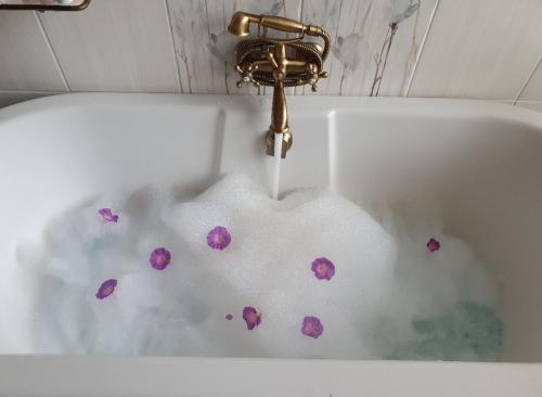 a bath tub filled with water with purple flowers in it at Charis on Beaumont in Margate
