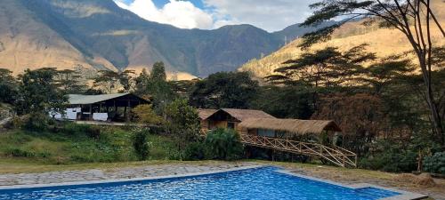 a resort with a swimming pool in front of a mountain at Araplay Lodge in Santa Teresa