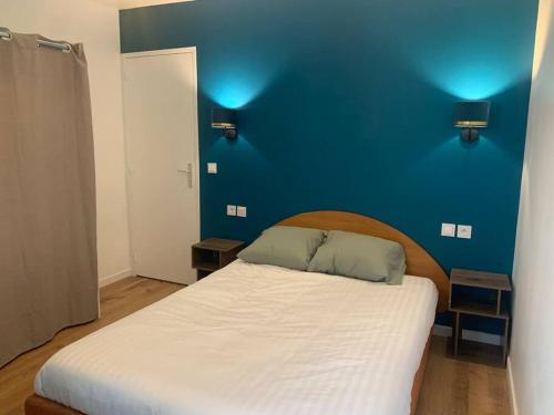 une chambre avec un lit blanc avec un mur bleu dans l'établissement Aubervilliers Paris, à Aubervilliers