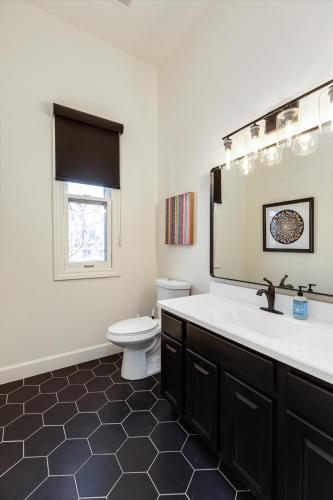 a bathroom with a sink and a toilet and a mirror at The Lumber Baron's Mansion: 2 King Suites, 2.5BA + Gym in Detroit