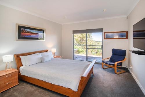 a bedroom with a bed and a chair and a window at Cantley at Flutes Estate, Margaret River in Wilyabrup