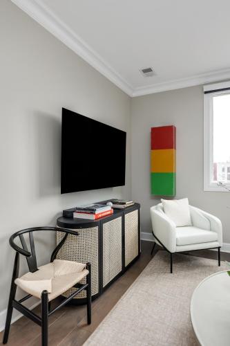 a living room with a tv and a chair at The Lumber Baron's Mansion: 2 King Suites, 2.5BA + Gym in Detroit