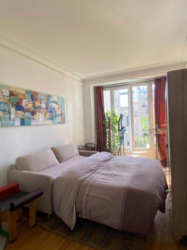 ein Schlafzimmer mit einem großen Bett und einem Fenster in der Unterkunft Appartement cozy pour 4 personnes - A 5 minutes de Paris in Levallois-Perret