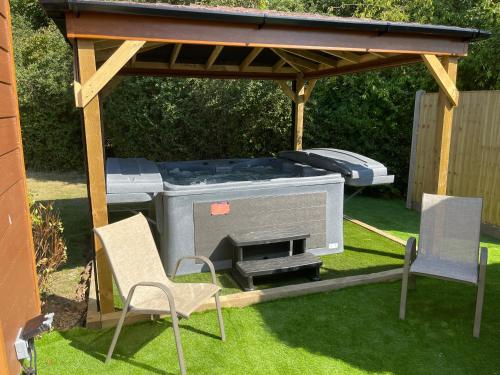 a gazebo with a grill and two chairs at Kingfisher Lodge in Grantham