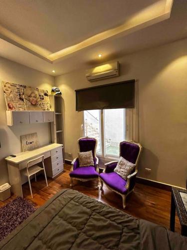 1 Schlafzimmer mit 2 lila Stühlen und einem Schreibtisch in der Unterkunft Stylish Apartment with garden in Kairo