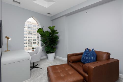 a living room with a brown leather couch and a window at The Lumber Baron's Mansion: 2 King Suites, 2.5BA + Gym in Detroit