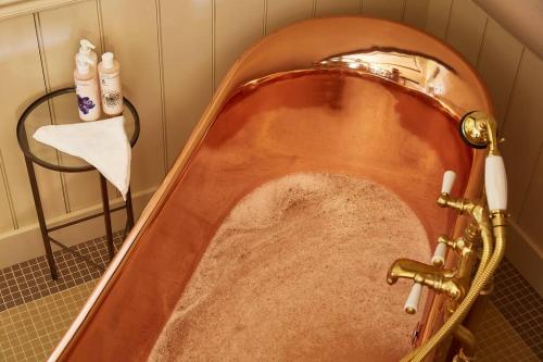 a copper bath tub with a sink in a bathroom at Dawn at The Sun Inn Felmersham, Our Signature Duplex Suite in Sharnbrook