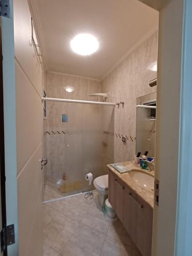 uma casa de banho com um chuveiro, um lavatório e um WC. em Suíte privativa em casa de família em São Paulo