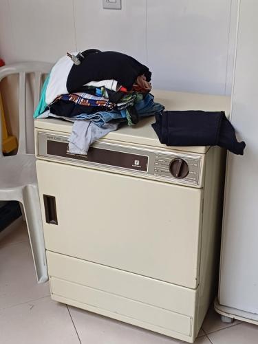 uma pilha de roupas sentadas em cima de uma máquina de lavar louça em Suíte privativa em casa de família em São Paulo