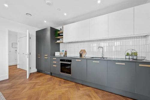 une grande cuisine avec des placards gris et des appareils blancs dans l'établissement Luxurious two-bedroom flat with scenic views, à Londres