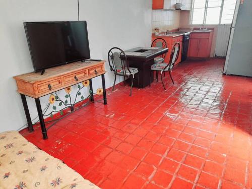 a living room with a television and a red tiled floor at Casa completa en Zapopan in Guadalajara