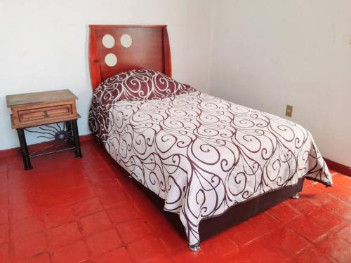 a bed with a black and white comforter and a table at Casa completa en Zapopan in Guadalajara