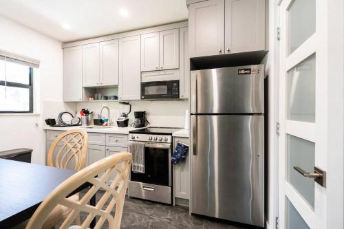cocina con armarios blancos y nevera de acero inoxidable en Cozy Place, en Miami