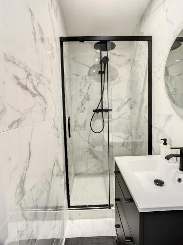 ein weißes Bad mit einer Dusche und einem Waschbecken in der Unterkunft Grand Cozy appart - proche métro Paris - proche spots touristiques in Ivry-sur-Seine