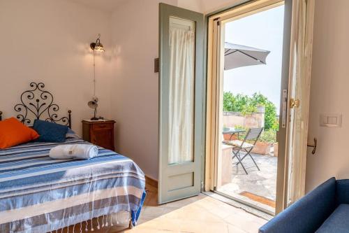 a bedroom with a bed and a sliding glass door at Le casette di Marò in Nunziata