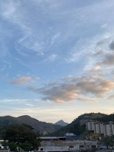 un cielo nublado con edificios y montañas en el fondo en Apê em Itaipava, en Petrópolis