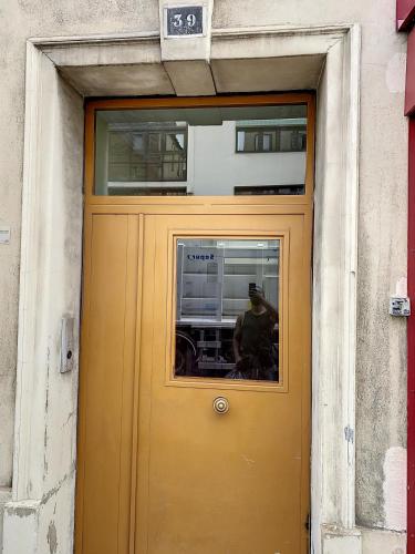 a yellow door with a man standing behind it at Grand Cozy appart - proche métro Paris - spots touristiques in Ivry-sur-Seine