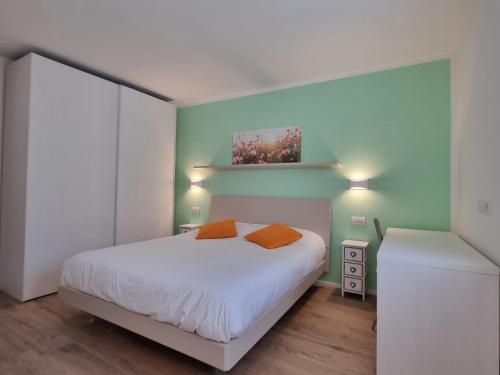 1 dormitorio con 1 cama con sábanas blancas y almohadas de color naranja en LaLunaMia B&B and Holiday Apartment, en Bedollo