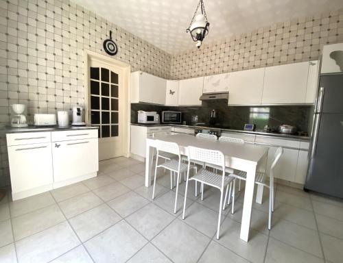 a kitchen with white cabinets and a table and chairs at Maison au calme, 6 voyageurs in Riorges