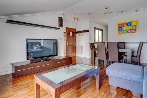uma sala de estar com uma televisão e uma mesa em Luminoso ático con terraza, Irún em Irun
