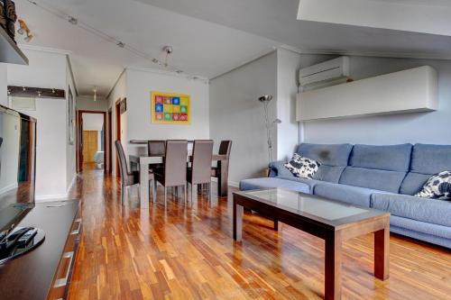 ein Wohnzimmer mit einem blauen Sofa und einem Tisch in der Unterkunft Luminoso ático con terraza, Irún in Irún