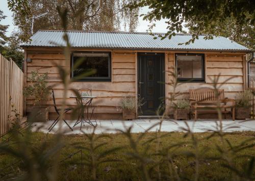 a wooden cabin with a table and chairs in a yard at Rose Hideaway - Forest of Dean Cosy Cabin Retreat in Yorkley