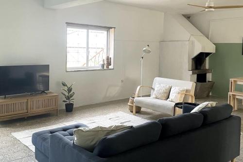 uma sala de estar com um sofá azul e uma televisão em Open and airy home 