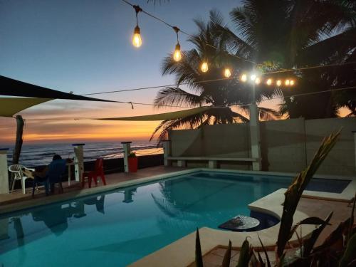 una piscina con vistas a la playa por la noche en MARDEORO BEACH HOUSE, en Barra de Santiago