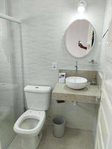 y baño con aseo, lavabo y espejo. en Duplex Encantador en Guarapari