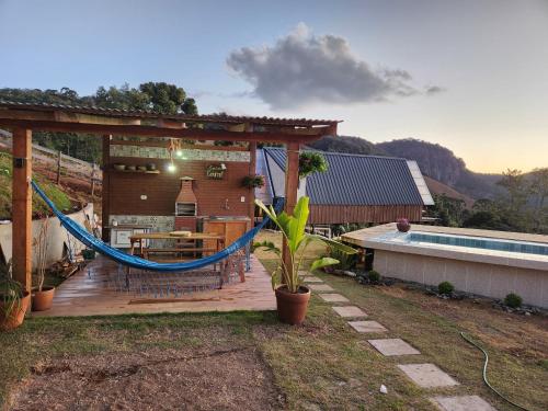 eine Holzterrasse mit einer Hängematte und einem Pool in der Unterkunft Cabana Alpes in São Bento do Sapucaí