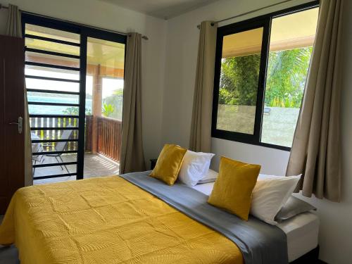 a bedroom with a bed with yellow sheets and windows at Villa Toa Pearl Bora Bora in Bora Bora
