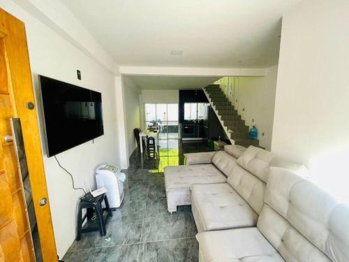 ein Wohnzimmer mit einem weißen Sofa und einem TV in der Unterkunft Casa aconchegante com piscina in Paraty