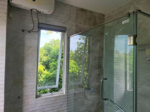 une salle de bain avec une fenêtre et une douche avec une porte vitrée dans l'établissement Tranquil Retreat Lux Villa in HungYen Countryside, à HÆ°ng YÃªn