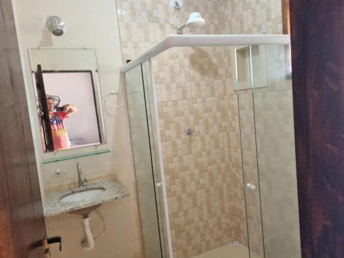 uma casa de banho com um chuveiro, um lavatório e um espelho. em Recanto Videira Rota do Vinho em São Roque