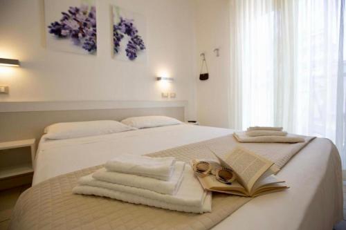 a bedroom with a bed with towels and a book at Hotel Elite in Cervia