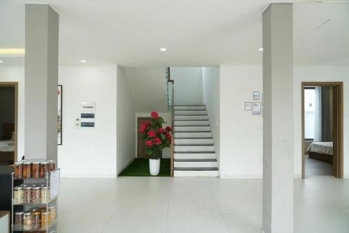 a white hallway with a staircase and a vase of flowers at Sea Villa - FLC Sam Son in Sầm Sơn