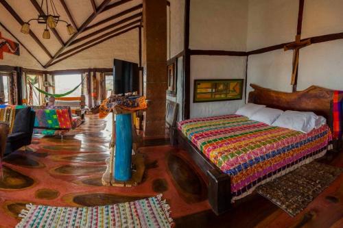 a bedroom with a large bed and a living room at Las Margaritas Salento in Salento