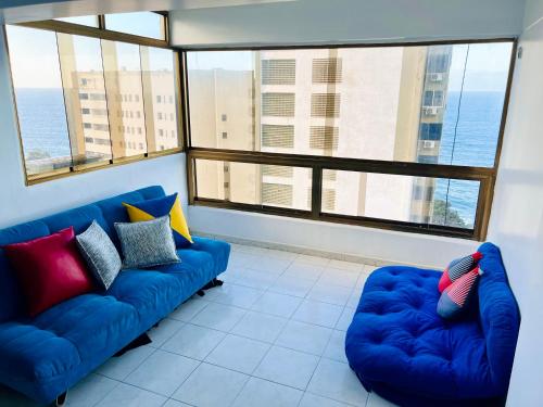 a living room with two blue couches and large windows at Casa de la Playa in Macuto