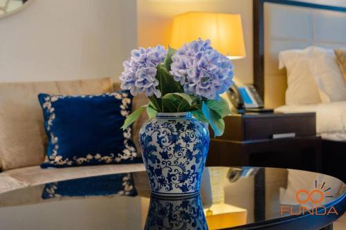 een blauwe en witte vaas met paarse bloemen op een tafel bij Luxe high floor Studio in address 36 in Dubai
