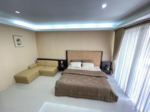 een slaapkamer met een groot bed en een bank bij Aryastri Villa in Bandung