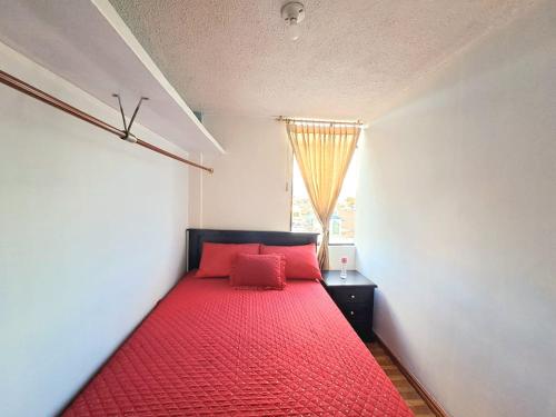 uma cama vermelha num quarto com uma janela em Alojamiento Comodo con Vista Espectacular em Riobamba