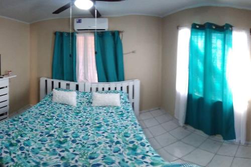 Schlafzimmer mit einem Bett mit grüner Bettwäsche und Vorhängen in der Unterkunft 3 Bedroom & Terrace Pool in La Ceiba