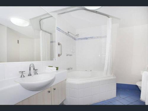 a white bathroom with a sink and a bath tub at Nautilus Resort - Private Apartment in Mooloolaba