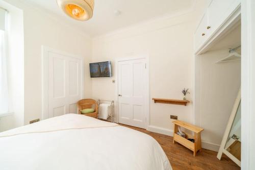 a white bedroom with a white bed and a wooden floor at Dreamy Town House Apartment in Dunkeld in Birnam
