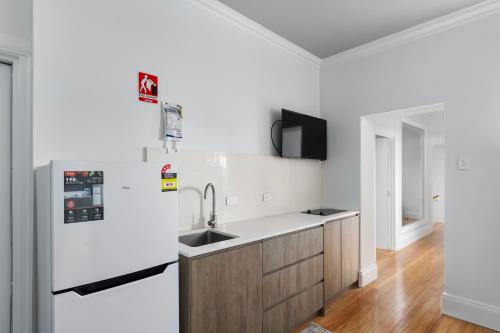 a white kitchen with a sink and a refrigerator at Costello Hotels Port Augusta in Port Augusta