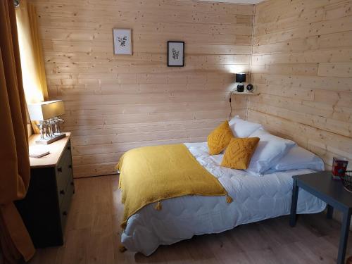 Un dormitorio con una cama con una manta amarilla. en Petit studio dans la prairie en Saint-Auban